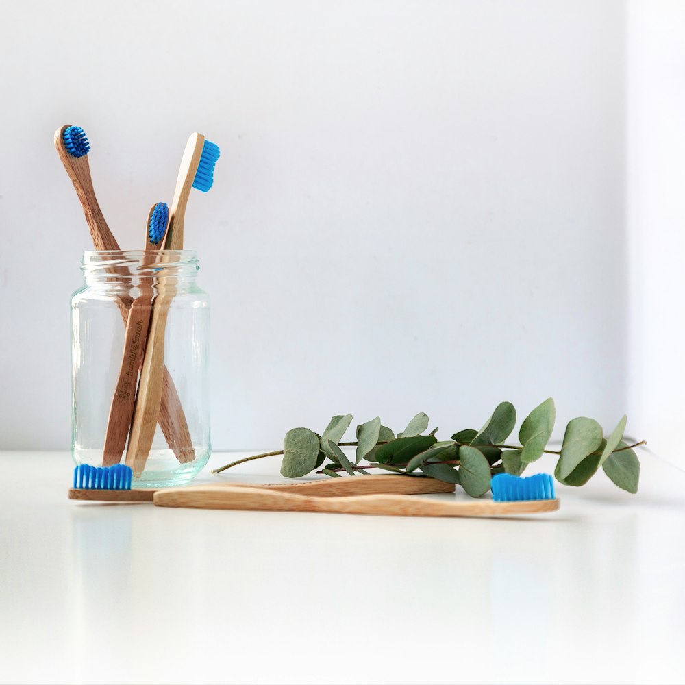 Brosse à dents bleue et blanche dans un pot en verre transparent