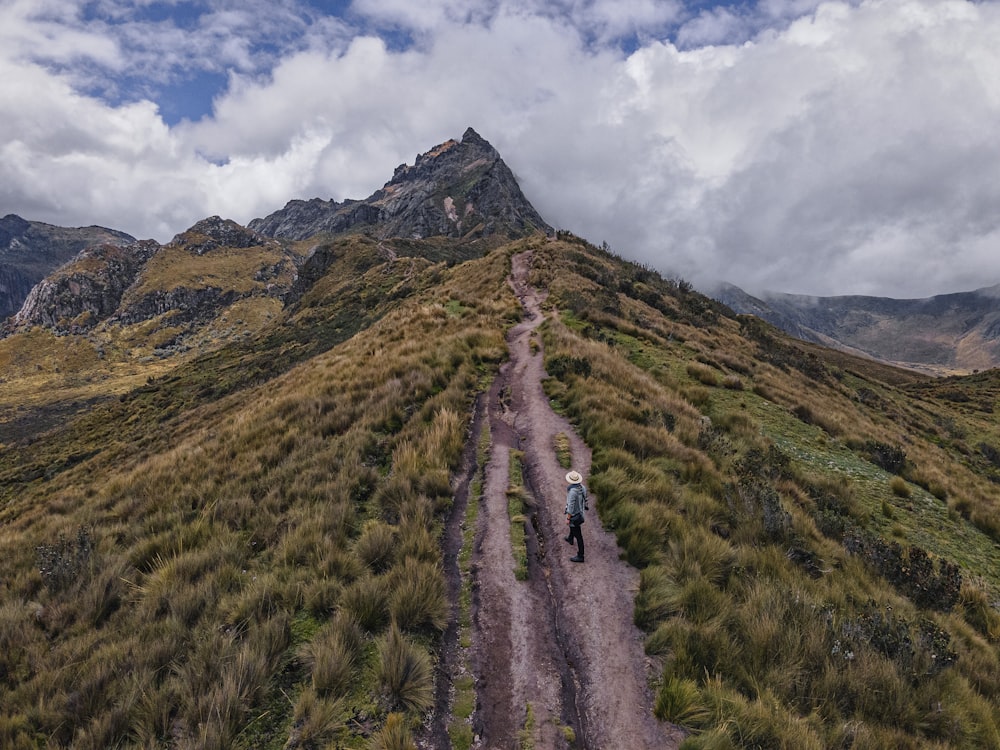 campo de grama verde perto da montanha sob nuvens brancas e céu azul durante o dia