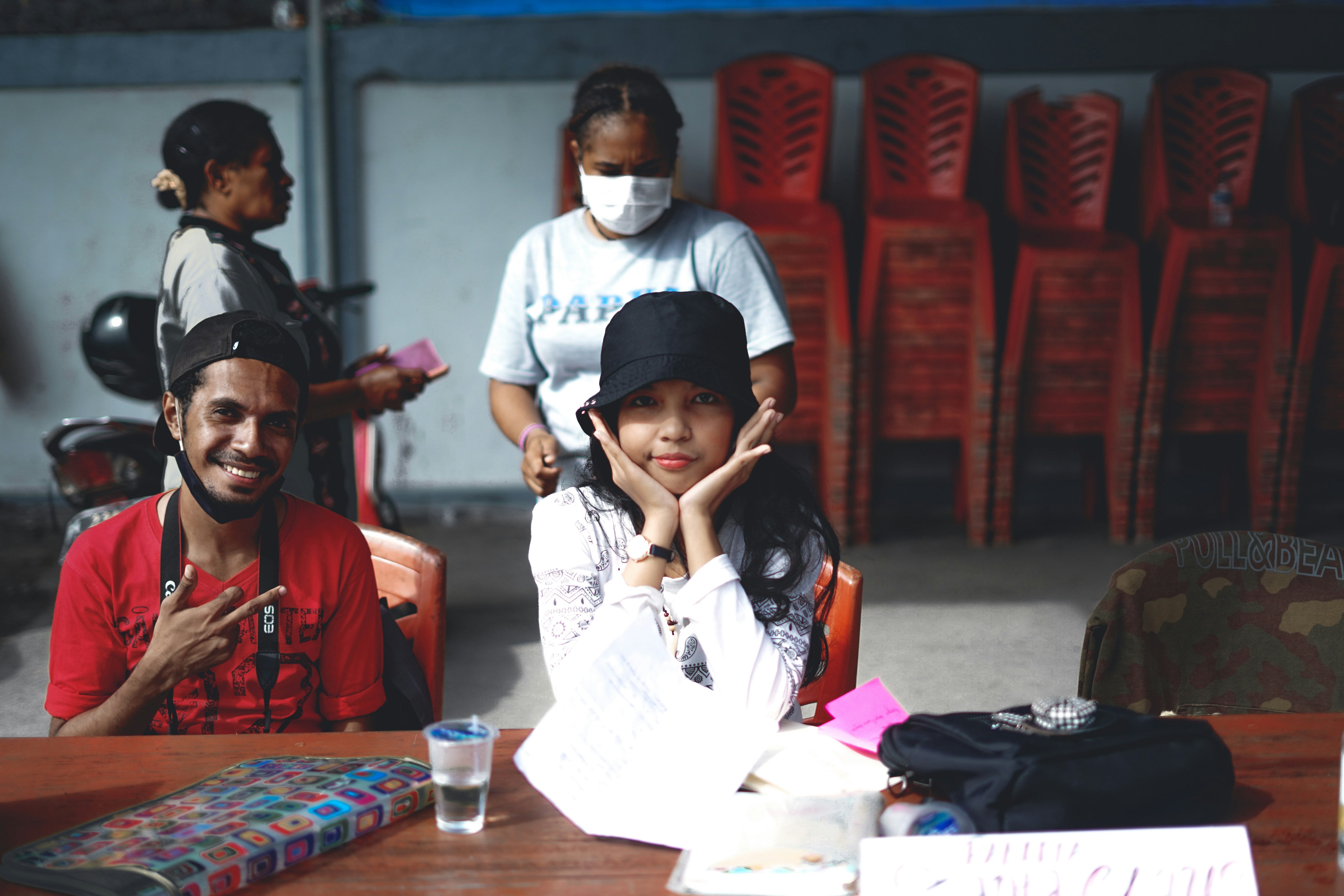 Mann im weißen Poloshirt sitzt auf rotem Plastikstuhl