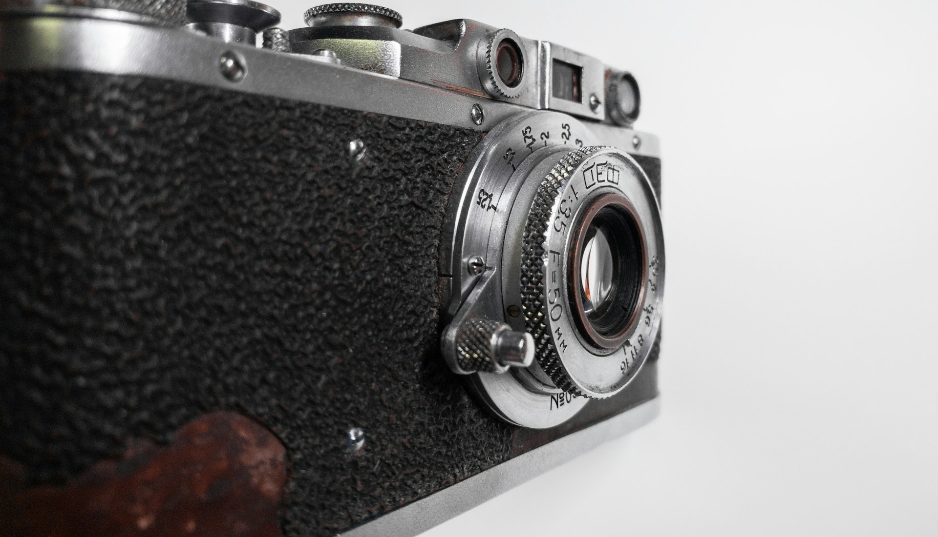 Close-up shot of a vintage film camera with sharp contrasts of black and white, highlighting textures and details.