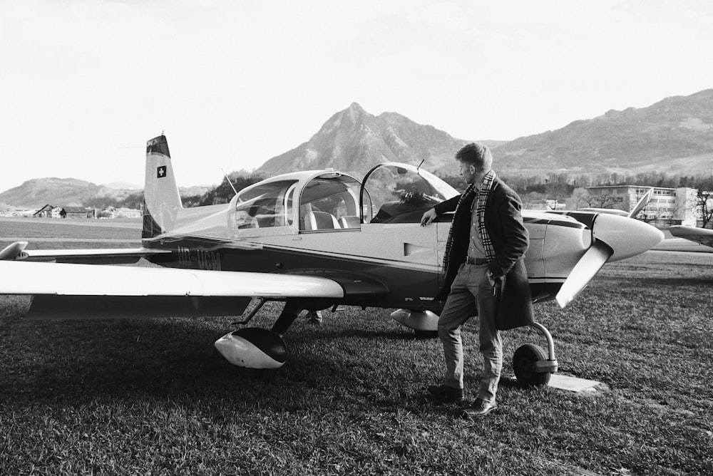 man in black jacket and pants standing beside airplane