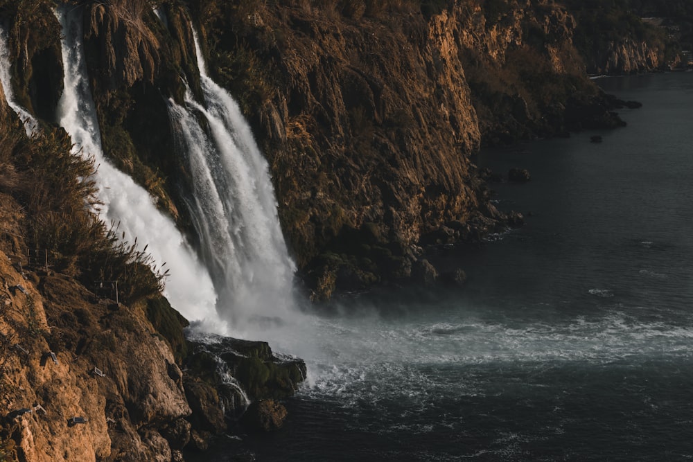 water falls on brown rocky mountain