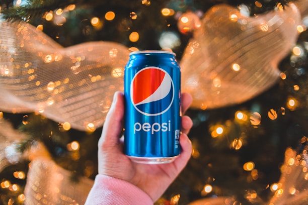 Close-up of hands holding colorful Carnavalera foam cans with festive decorations in the background.