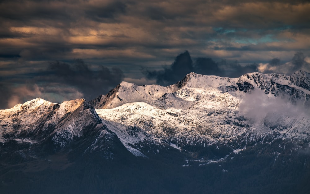 montagne enneigée sous un ciel nuageux pendant la journée