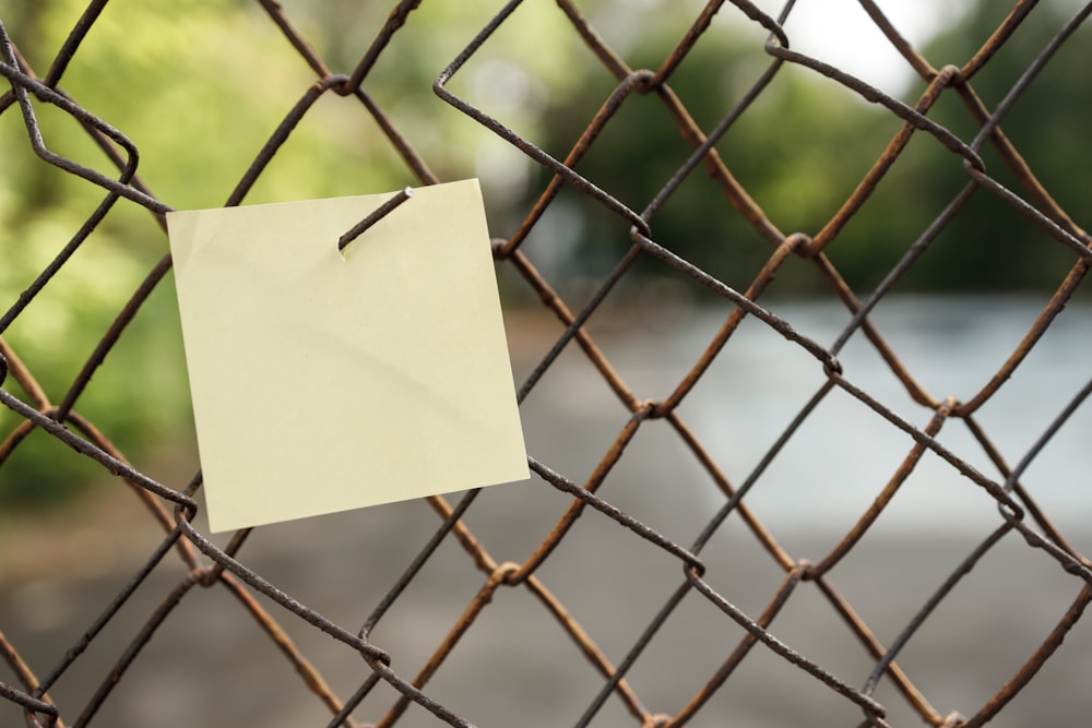 Note autocollante jaune sur clôture en métal gris