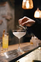 person holding clear wine glass with white liquid