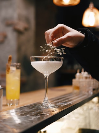 person holding clear wine glass with white liquid