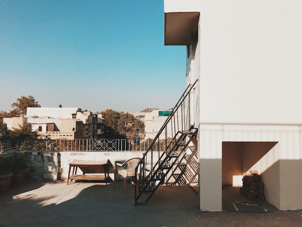 white plastic chairs near white concrete building during daytime