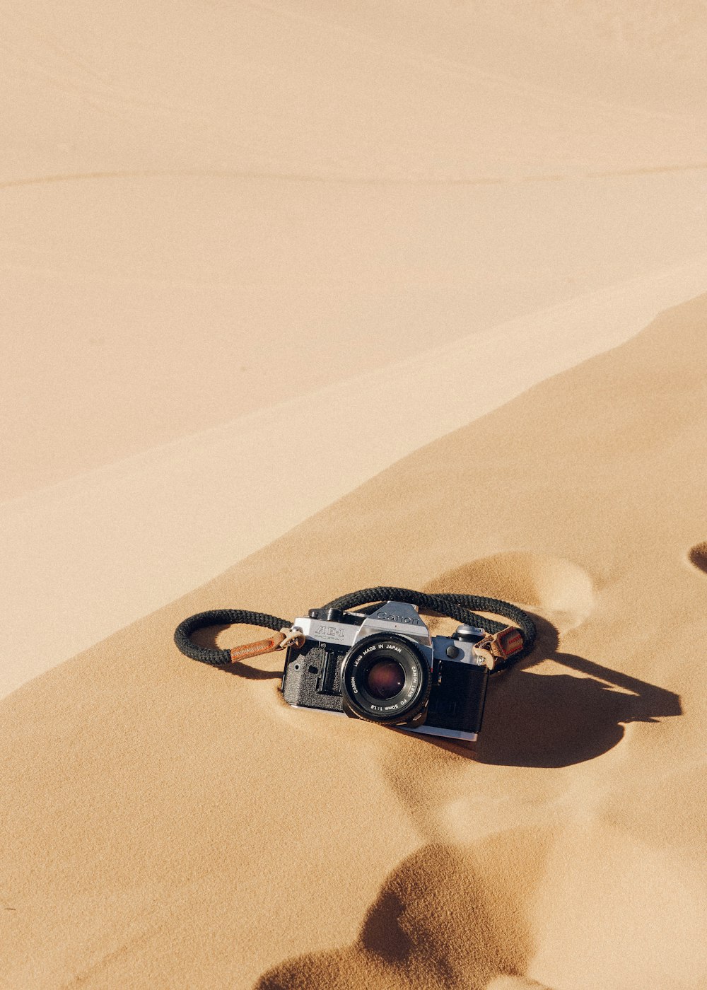 Schwarz-silberne DSLR-Kamera auf braunem Sand