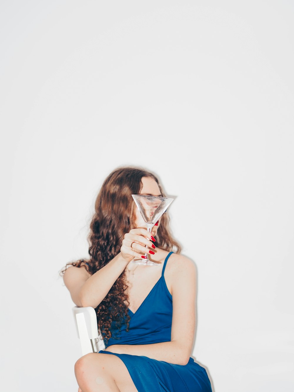 woman in blue sleeveless dress holding white disposable cup