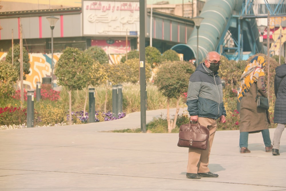 woman in black jacket and brown skirt carrying brown leather sling bag