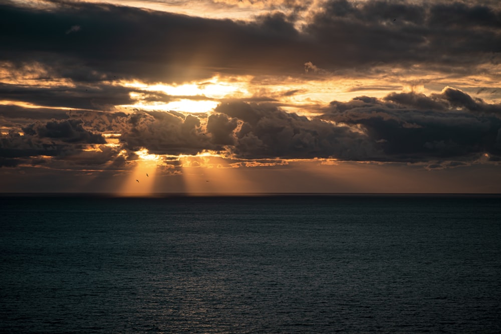 body of water under cloudy sky during sunset