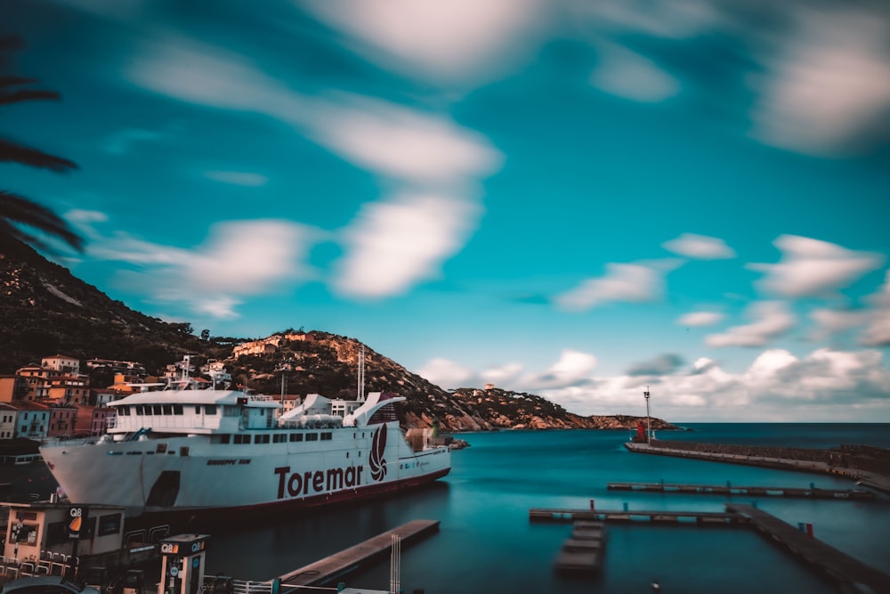 barco blanco y azul en el muelle del mar bajo el cielo azul durante el día