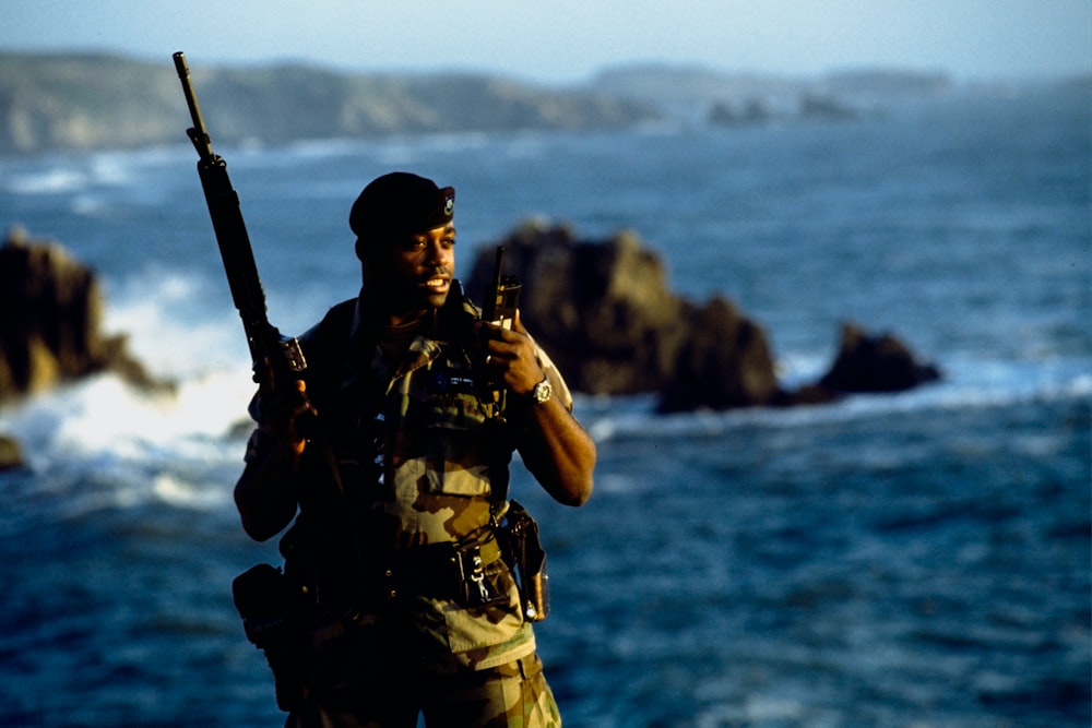 Hombre con uniforme de camuflaje verde y marrón sosteniendo un rifle negro