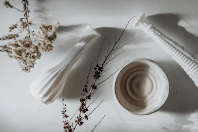 An arrangement of flower vessels with natural, wabi-sabi inspired shapes and muted tones on a wooden table.