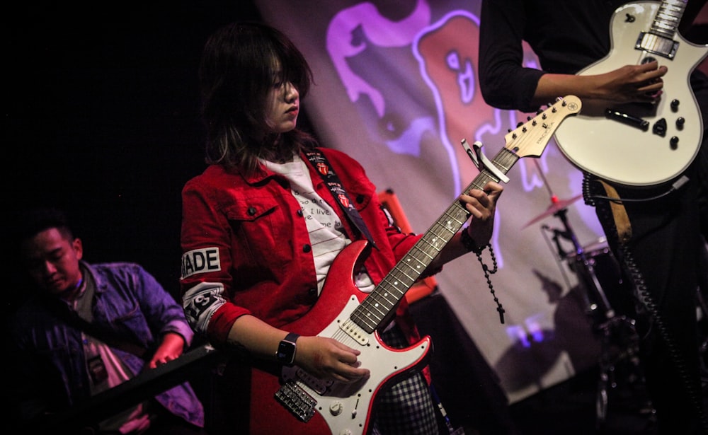 woman in red and white jacket playing electric guitar