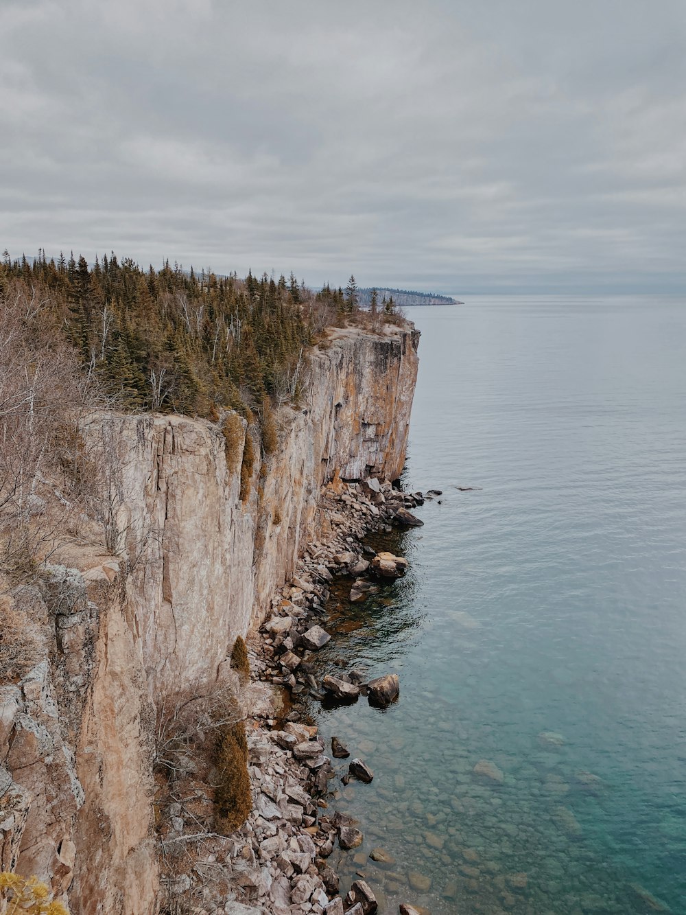 a rocky cliff overlooks the ocean on a cloudy day