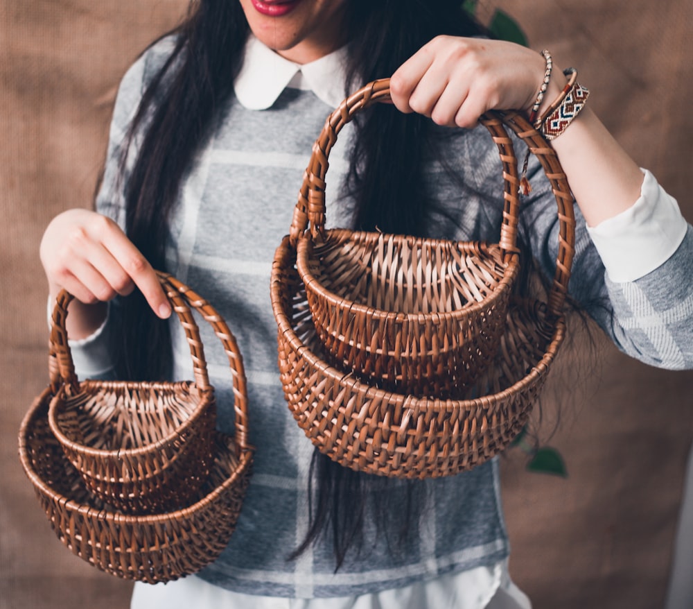 woman in gray long sleeve shirt holding brown woven basket