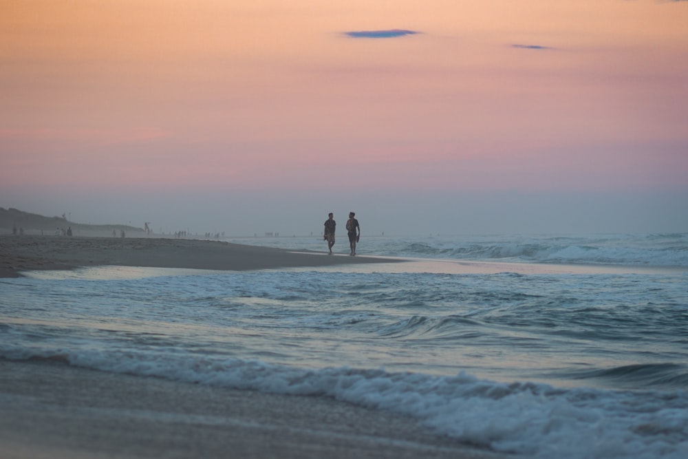 2 person walking on beach during daytime