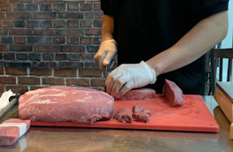 Close-up of a worker inspecting meat quality wearing sanitary gloves and uniform.