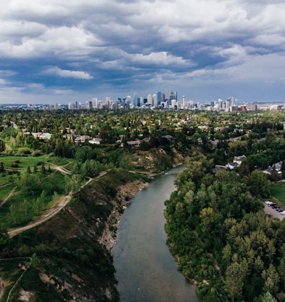 aerial view of city buildings and trees under cloudy sky during daytime