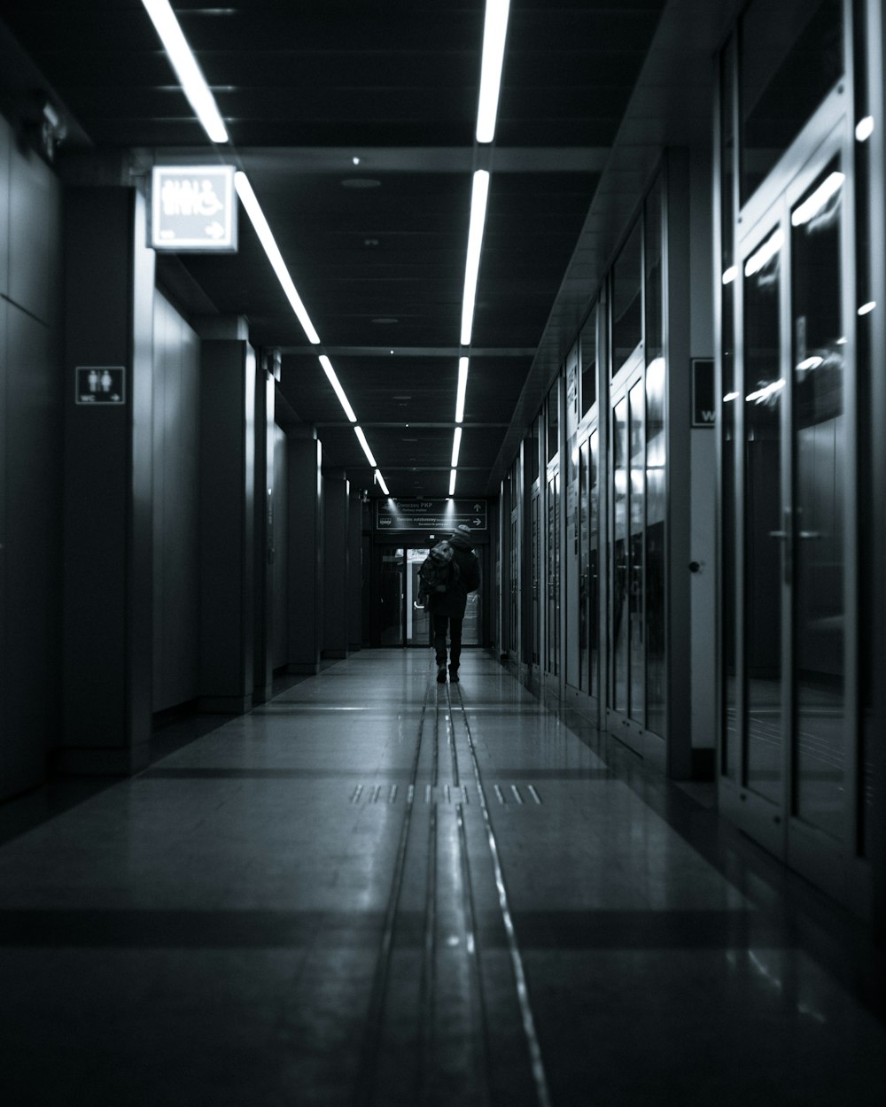 grayscale photo of man walking on hallway