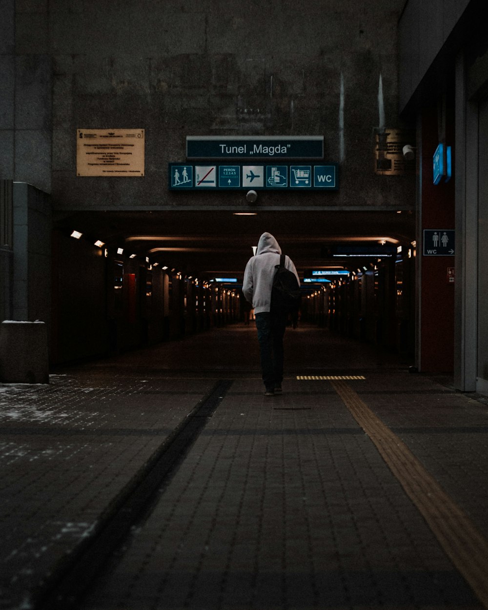 man in white dress shirt and black pants standing on sidewalk during night time