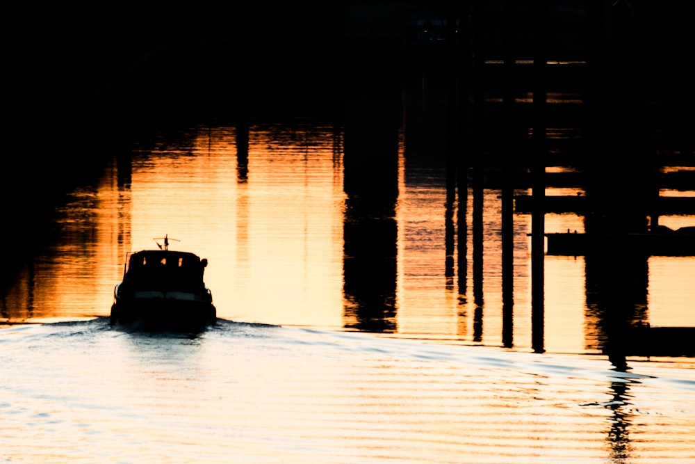 silhouette of boat on water during sunset