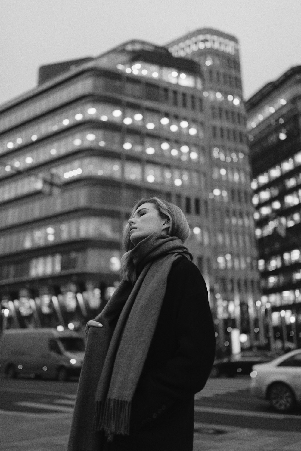 woman in black coat standing in the city in grayscale photography