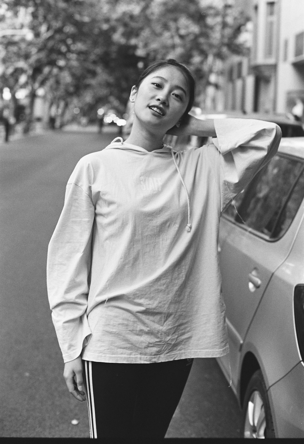 grayscale photo of woman in long sleeve shirt standing on road