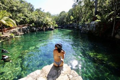 woman in black bikini standing on rock near river during daytime