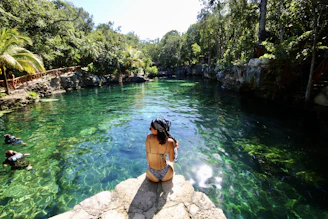 woman in black bikini standing on rock near river during daytime