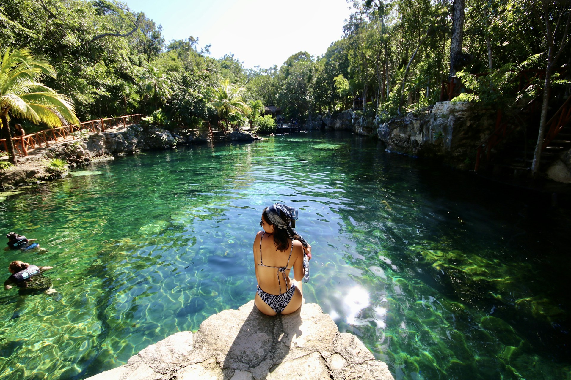 woman in black bikini standing on rock near river during daytime