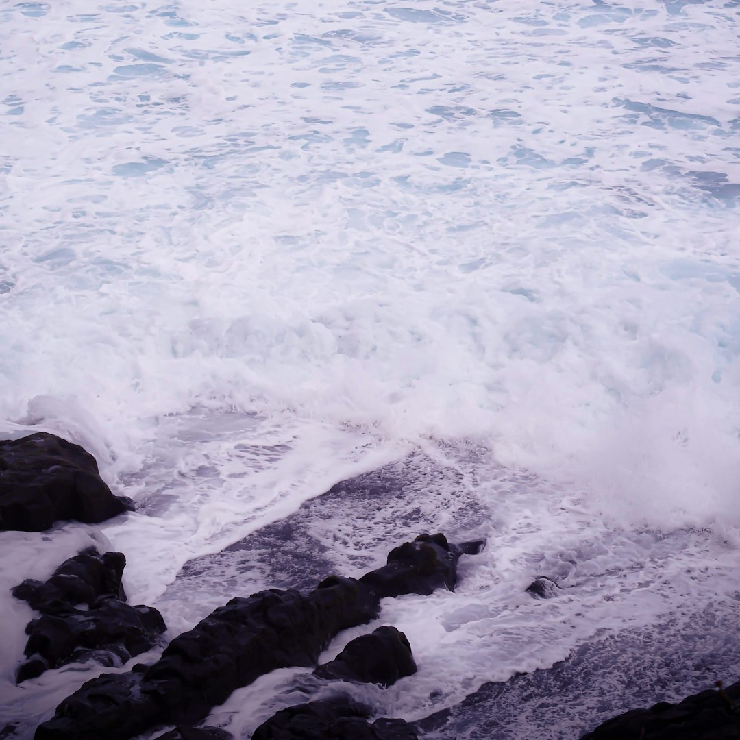 ocean waves crashing on black rocks during daytime