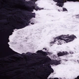 Close-up of crashing waves against dark volcanic rocks.