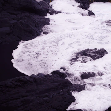 Close-up of crashing waves against dark volcanic rocks.