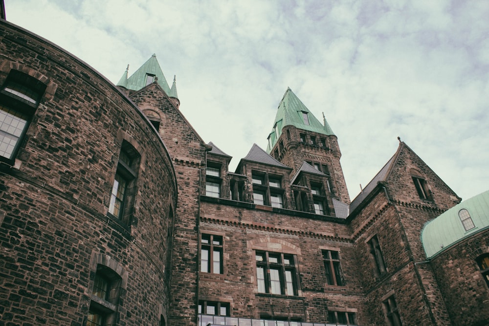 brown brick building under white clouds during daytime