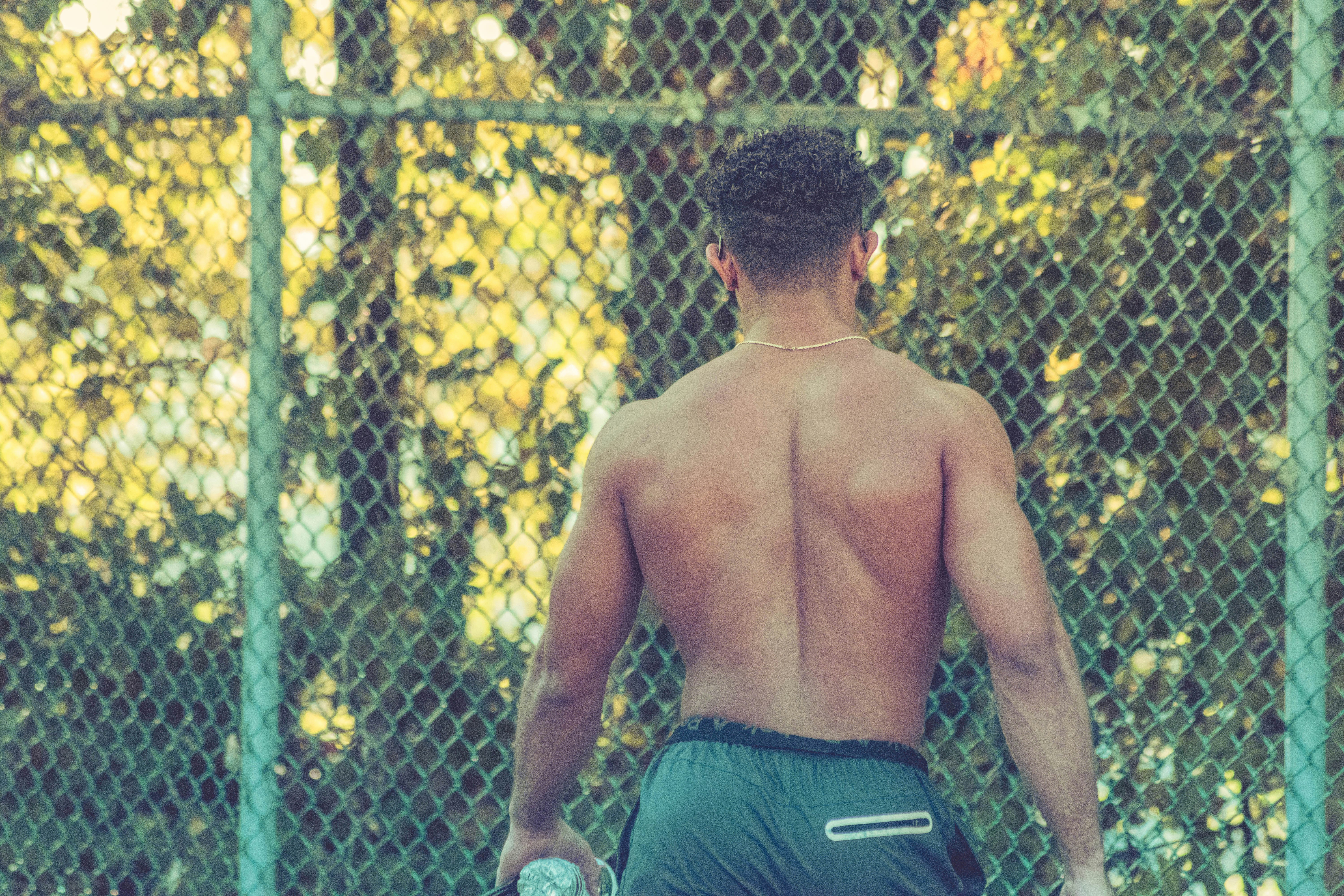 topless man in green shorts sitting on chair