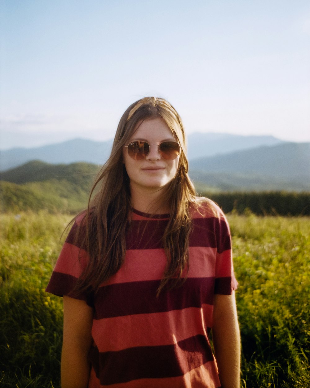 woman in red and black stripe shirt standing on green grass field during daytime