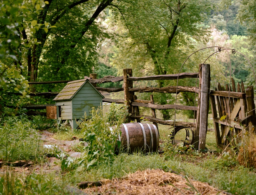 brown wooden barrel near brown wooden fence surrounded by green trees during daytime