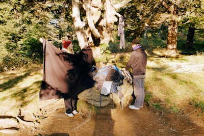 A camper setting up a tent in a lush forest at dawn.