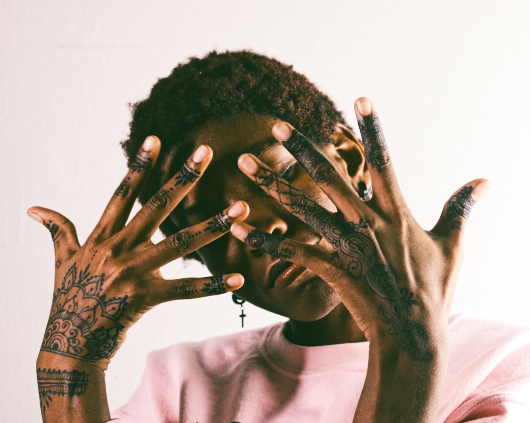 man in white crew neck shirt with black tattoo on his left hand