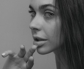 grayscale photo of woman with her hand on her chin