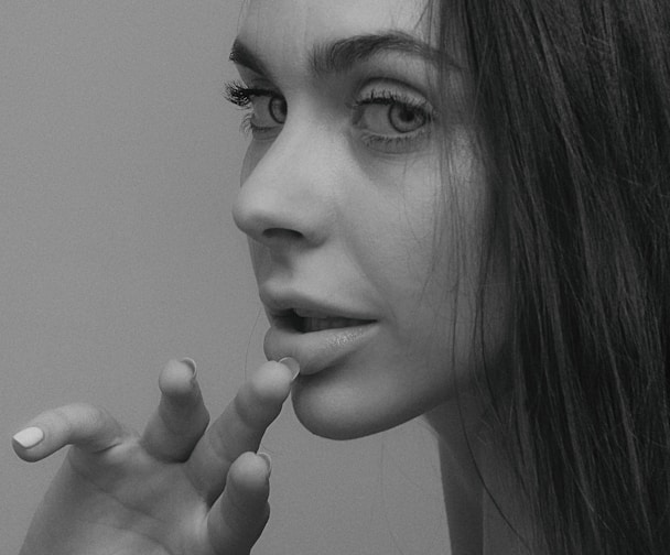 grayscale photo of woman with her hand on her chin