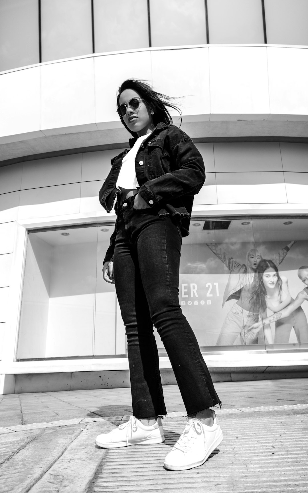 woman in black jacket and black denim jeans standing near glass window