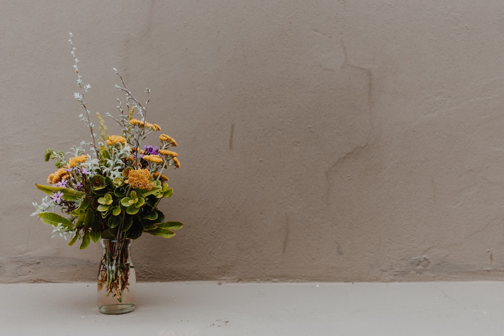 yellow and white flowers in clear glass vase