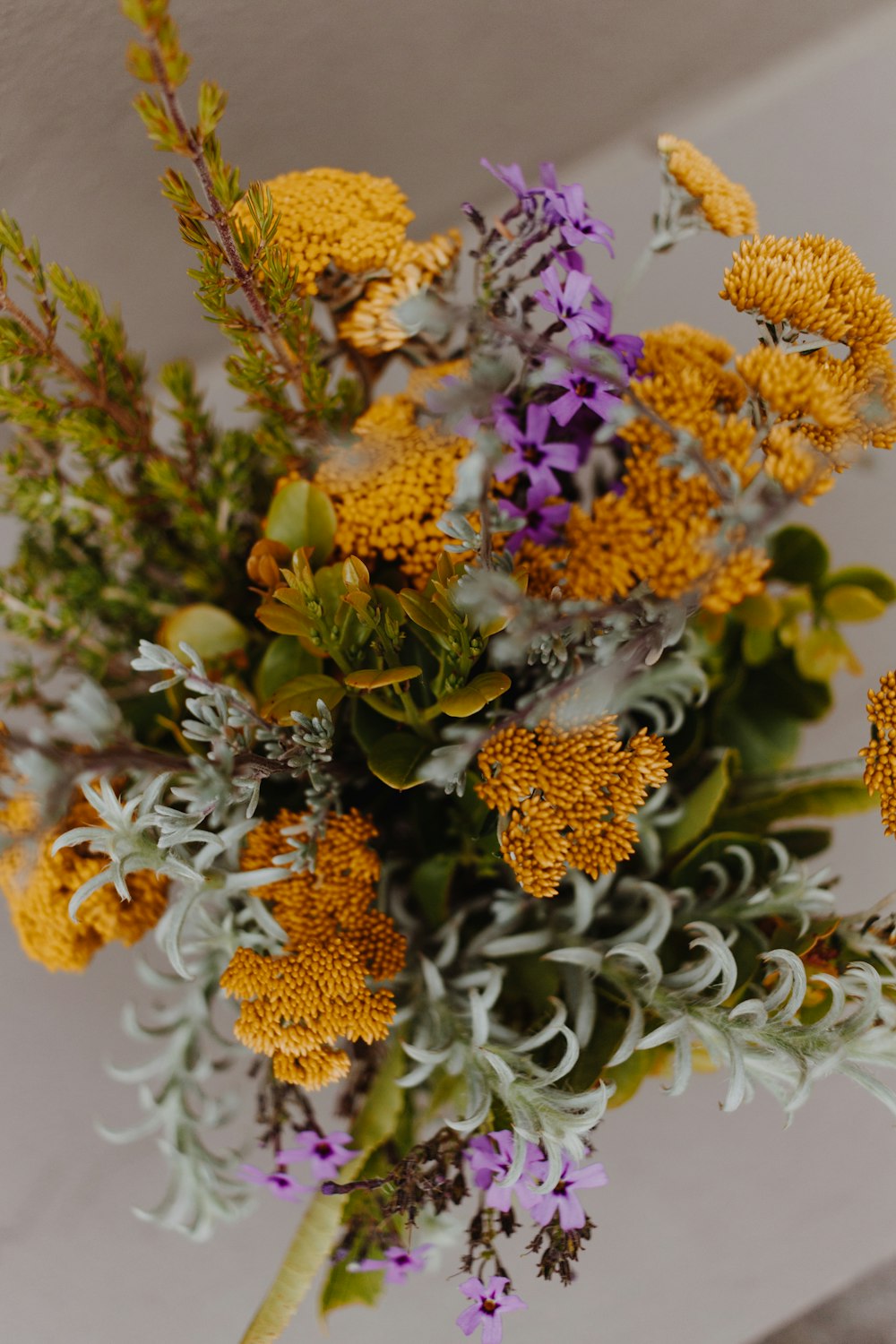 yellow and purple flowers in white ceramic vase