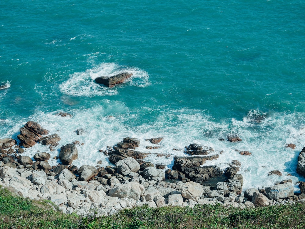 rocky shore with ocean waves crashing on rocks during daytime