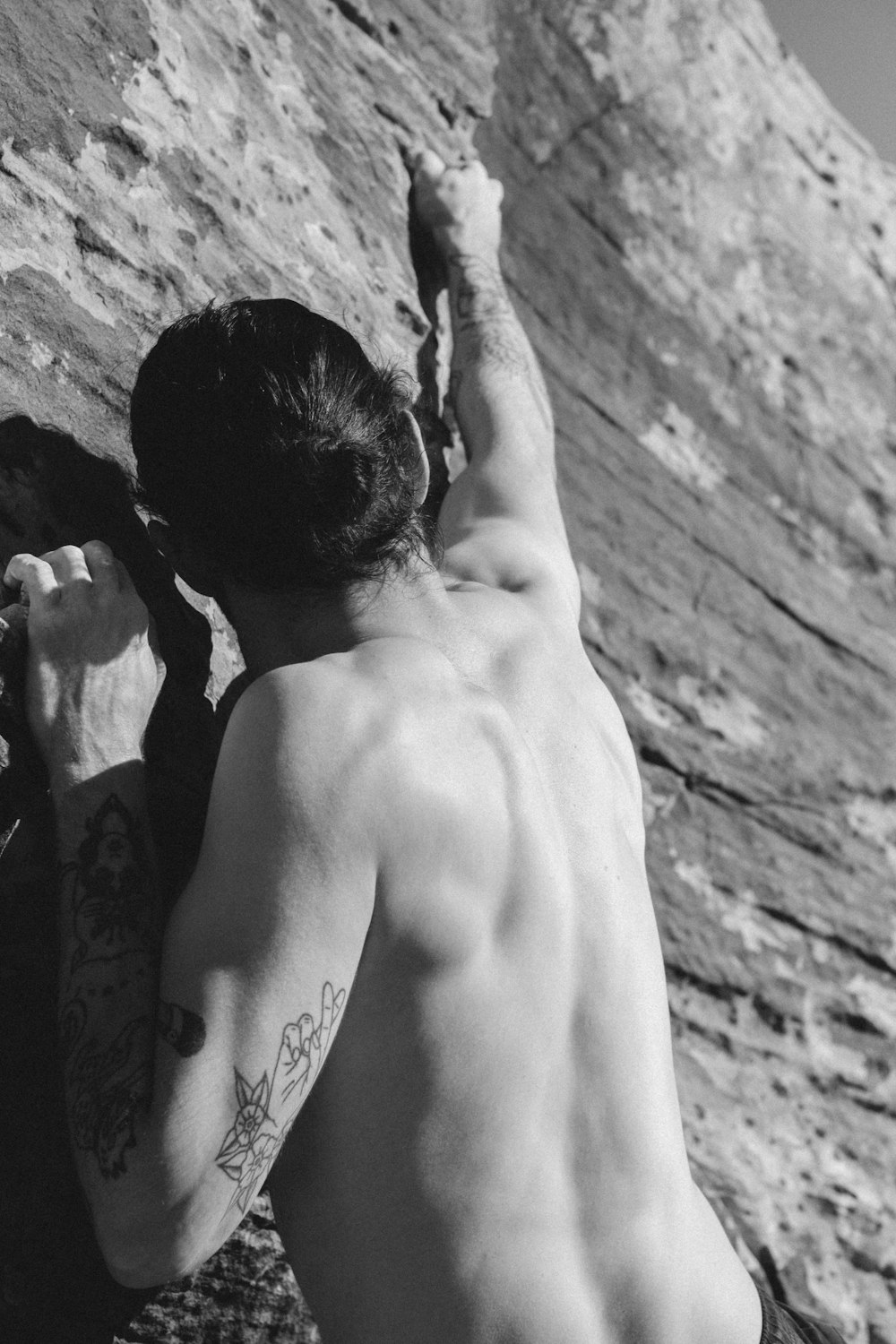Foto en escala de grises de un hombre en topless con un tatuaje en la espalda