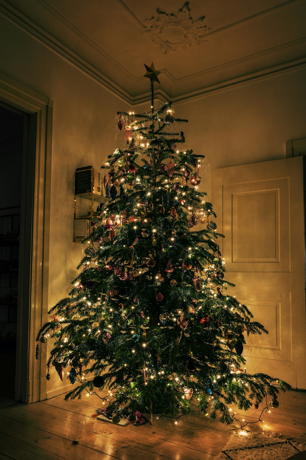 uma árvore de Natal iluminada no canto de uma sala